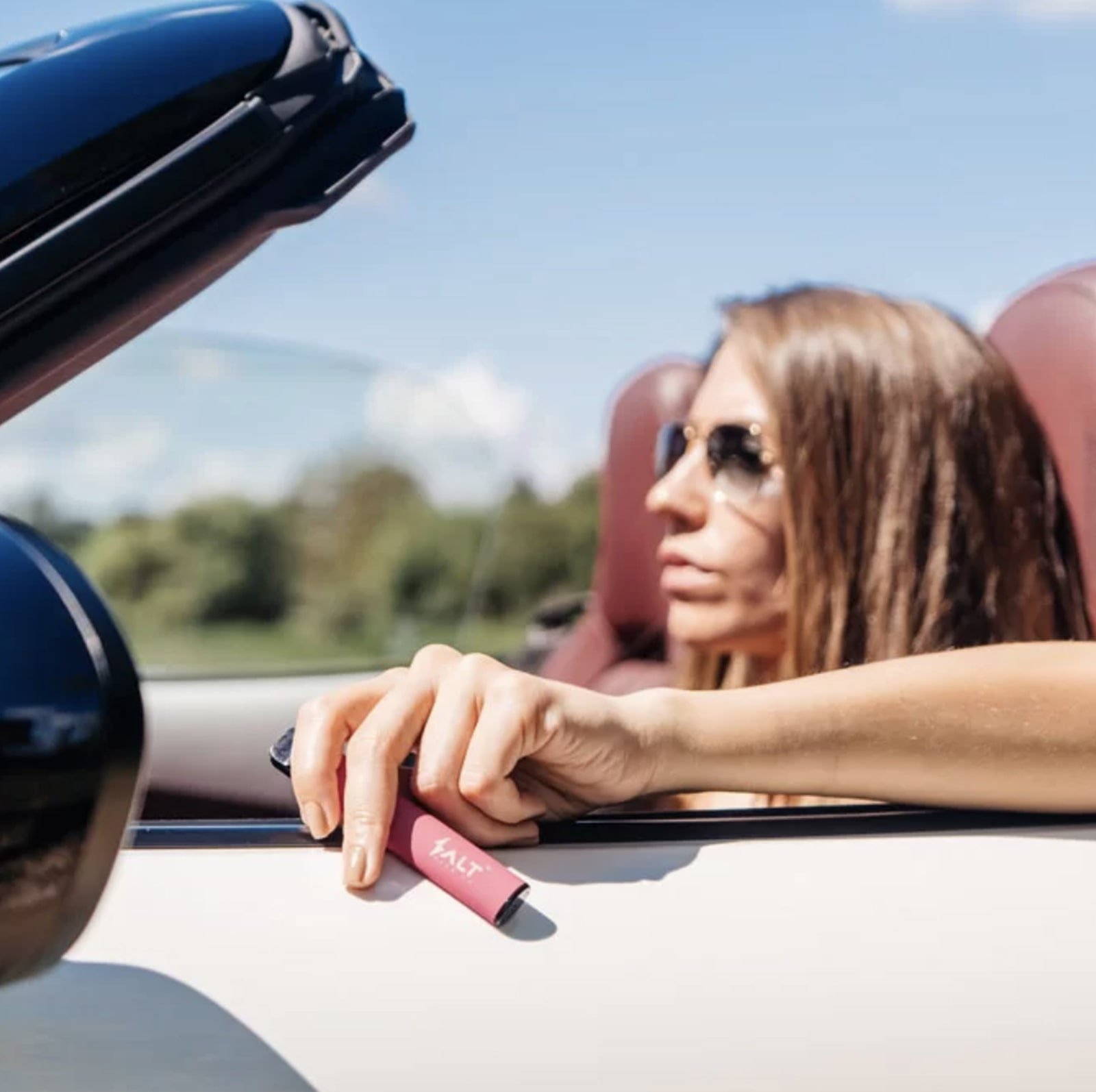 Girl driving a car and holding a vape pod in one hand